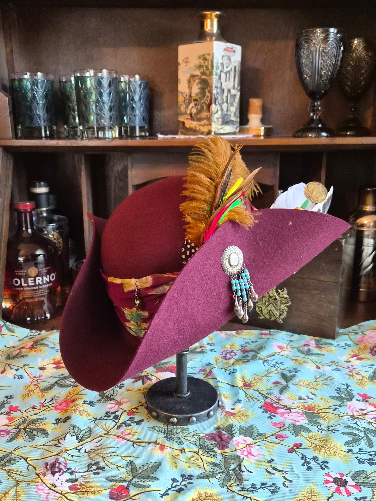 Burgundy wool tricorn hat with feather plume and turquoise beaded concho